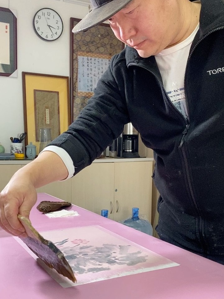 李春风在工作室进行手工装裱操作